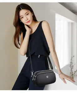 Details of black leather multi-compartment crossbody phone bag for women with sleek shoulder strap.