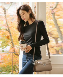 Detail view of genuine leather double-layer crossbody phone bag with metal heart logo.