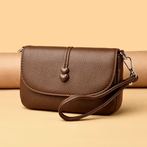 Piccola borsa quadrata marrone con texture in pelle, bottoni a cuore e cinturino da polso donna.