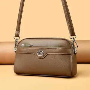 Genuine leather brown cross-body phone bag with silver heart emblem and double zipper.