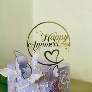 Detailed view of gold acrylic Happy Anniversary cake topper with decorative butterflies.