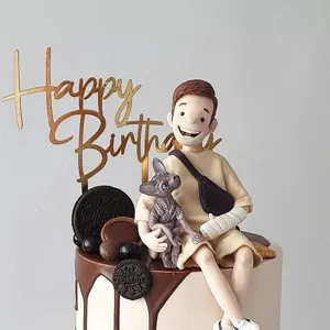 Detail view of custom birthday cake topper with gold acrylic sign and cute figurine.