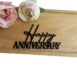 Black acrylic Happy Anniversary cake topper with artificial peony flowers and wooden tray.