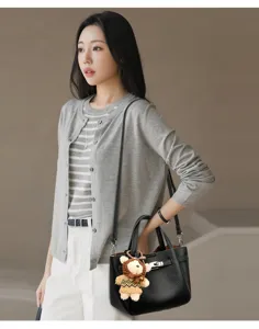 Leather lock handbag detail view, stylish bucket bag with knit bear pendant for women.