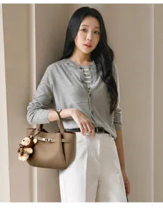 Detail shot of stylish leather handbag with metal lock and cute bear pendant, elegant look.