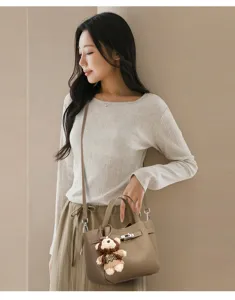Elegant women leather lock handbag crossbody bag with cute bear pendant for daily fashion outfit.