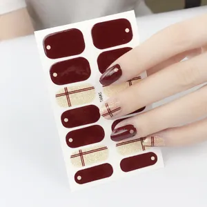 Close-up detail of burgundy and plaid glitter nail wraps, showing glossy texture and application.