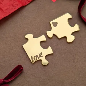 Detail shot of gold mirror acrylic puzzle cake topper with love engraving and heart cutout.