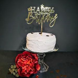 Nahaufnahme des goldenen Acryl HAPPY Birthday Kuchendekorationssteckers auf weißem Kuchen.