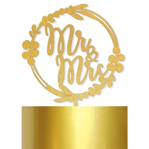 Cake topper doré pailleté Mr & Mrs avec couronne florale pour décoration de fête de mariage.