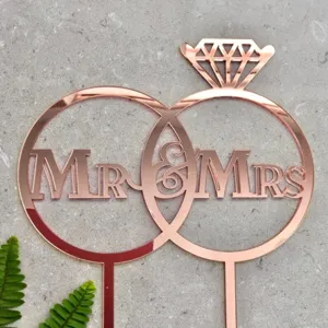 Detailed view of rose gold acrylic Mr & Mrs wedding cake topper with double rings and diamond.