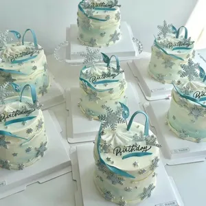 Detailed view of trendy ins-style birthday cake with acrylic snowflakes and blue ribbon decor.