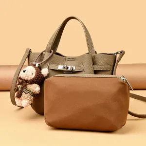 Stylish leather lock bucket handbag set with cute bear pendant for daily practical wear.