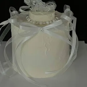 Detail shot of white cake with delicate ribbons, pearl beads and crystal moon decoration.