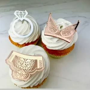 Gros plan de cake toppers en acrylique avec bague argentée et design de lingerie or rose.
