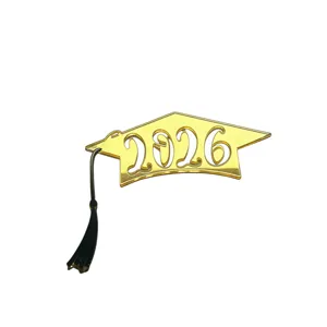Gold acrylic 2026 graduation cap cake topper detail view with black tassel decoration.