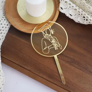Details of the golden acrylic female graduate cake topper showing a clean line art design.