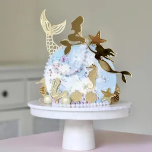 Detalle topper tarta sirena, decoración dorada temática océano concha
