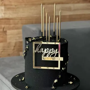 Gold acrylic happy birthday cake topper set with black frosted cake and candles for party decor.