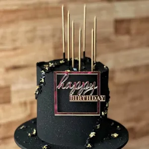 Black cake with gold candles and acrylic happy birthday topper, perfect party decoration.