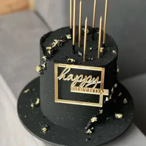Black birthday cake with gold candles and acrylic happy birthday topper for party decor.