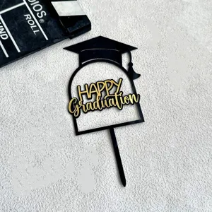 Close up of black and gold acrylic graduation cake topper with cap design for party.