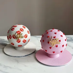 Close-up of gold Love You acrylic cake topper on romantic spherical mousse cake dessert.