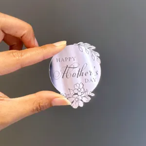 Close-up detail of a clear acrylic cake topper featuring engraved Mother's Day text and floral.