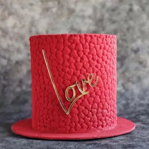 Detail shot of a red textured cake with gold love acrylic topper for Valentine day decor.