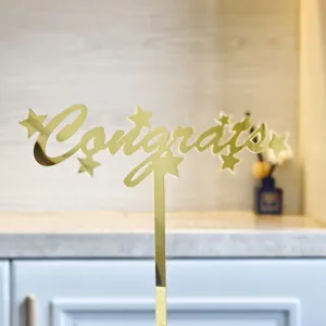 Detailaufnahme des goldenen Acryl Congrats Kuchendeckers für Abschlussfeier Dekoration.