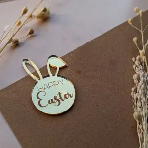 Detail shot of golden acrylic Easter bunny cake topper with Happy Easter text decoration.