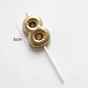Gold number 8 birthday candle detail shot, miniature cake topper with white support stick.