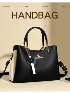 Detailed view of the stylish color-block handbag with elegant pendant and sturdy handle.