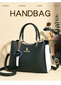 Detailed view of colorblock leather handbag, stylish dual handles and charm pendant.