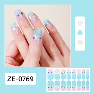 Detail view of gradient blue and pink nail wraps with cute star and strawberry patterns.