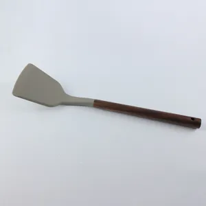 Spatule en silicone avec manche en bois sombre, ustensile de cuisine résistant détail.