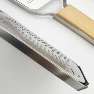 Stainless steel cheese grater detail, sharp etched blade and smooth wooden handle closeup.