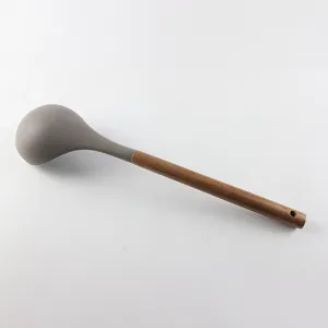Détail de louche à soupe en silicone avec tête grise résistante et manche en bois de noyer.