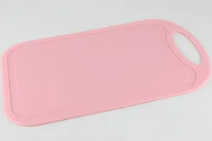 Pink plastic cutting board detail, anti-slip kitchen tool with convenient hanging hole.