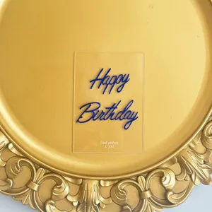 Detail view of transparent acrylic Happy Birthday cake topper with blue layered text.