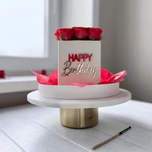 Detail shot of square birthday cake box with red roses and acrylic Happy Birthday topper.