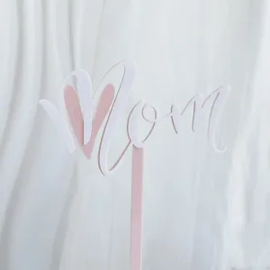 Primer plano del adorno de tarta de acrilico rosa con diseno de corazon para madres.