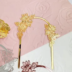 Goldener Acryl-Kuchenaufsatz Bogen Detail mit filigranen Blumen für Feierlichkeiten.