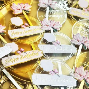 Closeup of clear acrylic cake toppers with floral UV print and ribbon for party celebration.