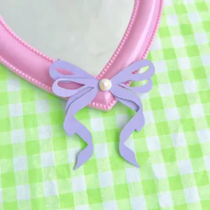 Adorno de tarta con lazo de papel morado y gema, vista de detalle para decoración.