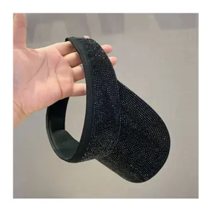 Primer plano detalle de un sombrero visera solar vacío de estrás negro con textura brillante.