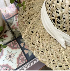 Primo piano dettagliato di un cappello di paglia intrecciato con nastro bianco estivo.