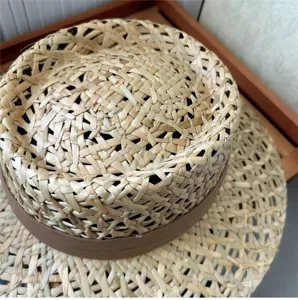 Dettaglio di cappello di paglia francese con trama naturale e nastro marrone.