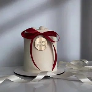 Acrylic happy birthday cake topper disc with red ribbon, elegant party decoration detail.