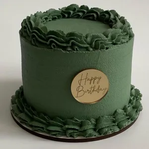 Green frosted birthday cake decorated with a stylish gold acrylic Happy Birthday topper disc.